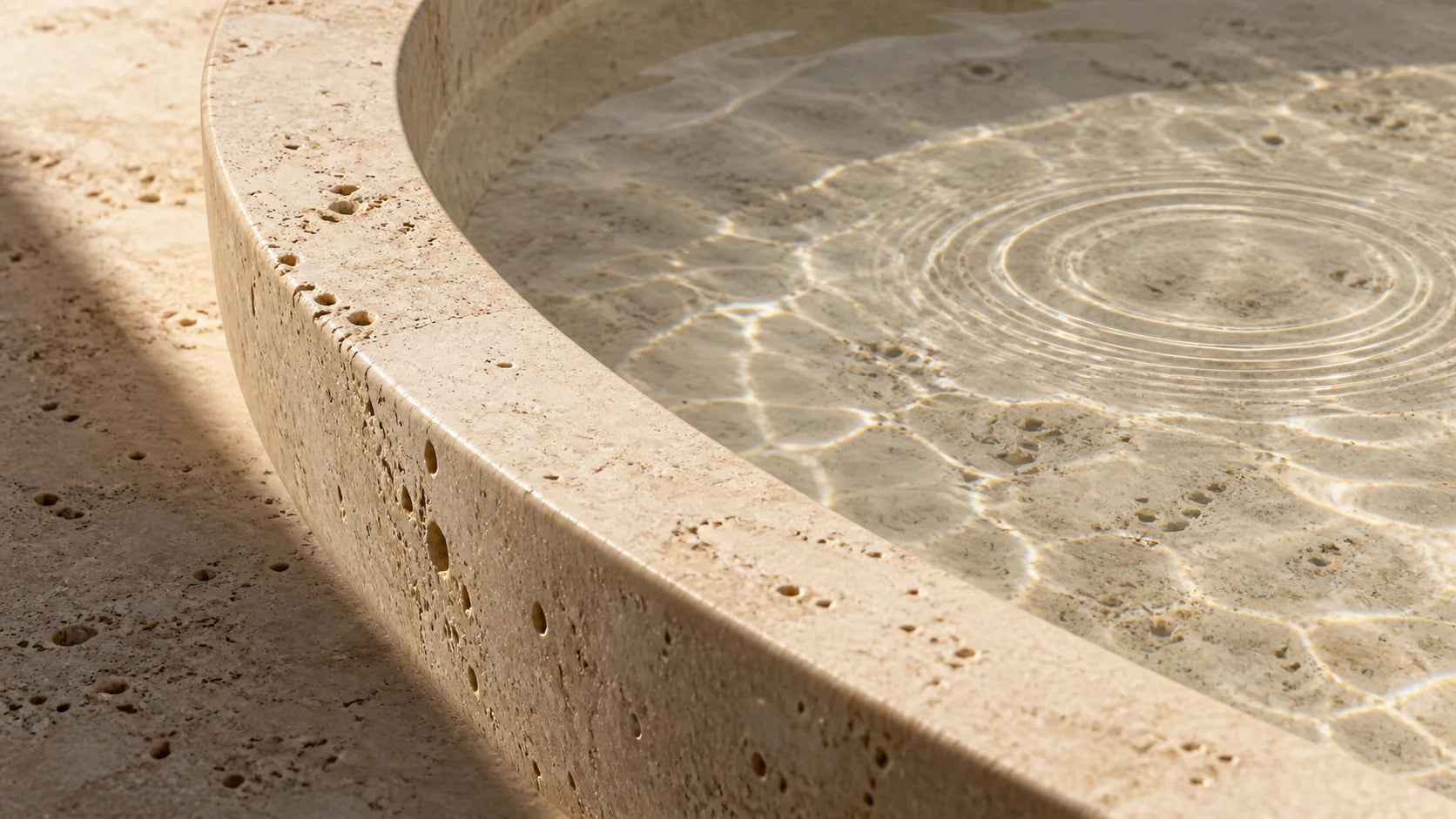 Lavalió Materialstudie: Licht und Wasserringe in einer Schale aus Travertin.